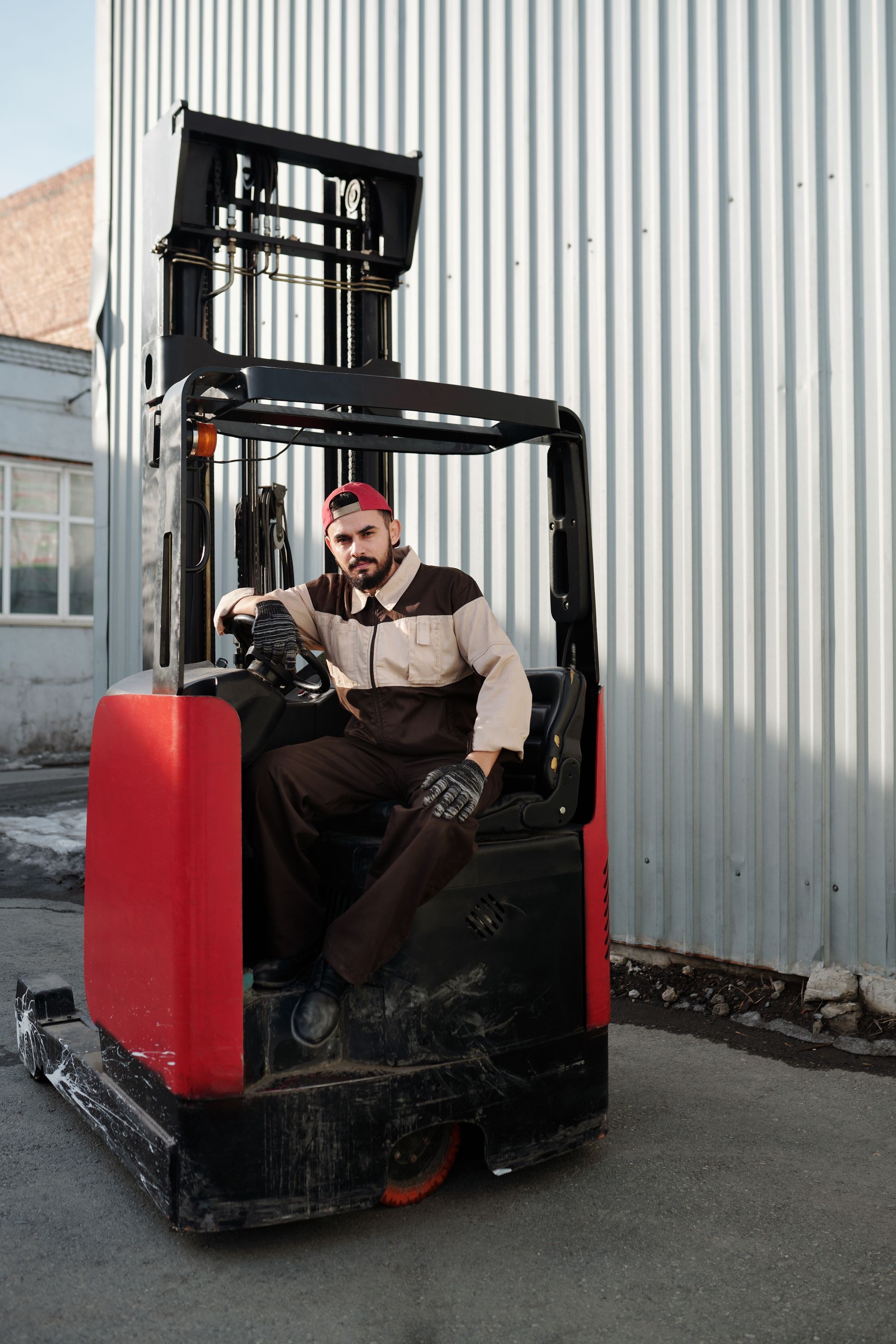 A forklift operator works beside an industrial warehouse.